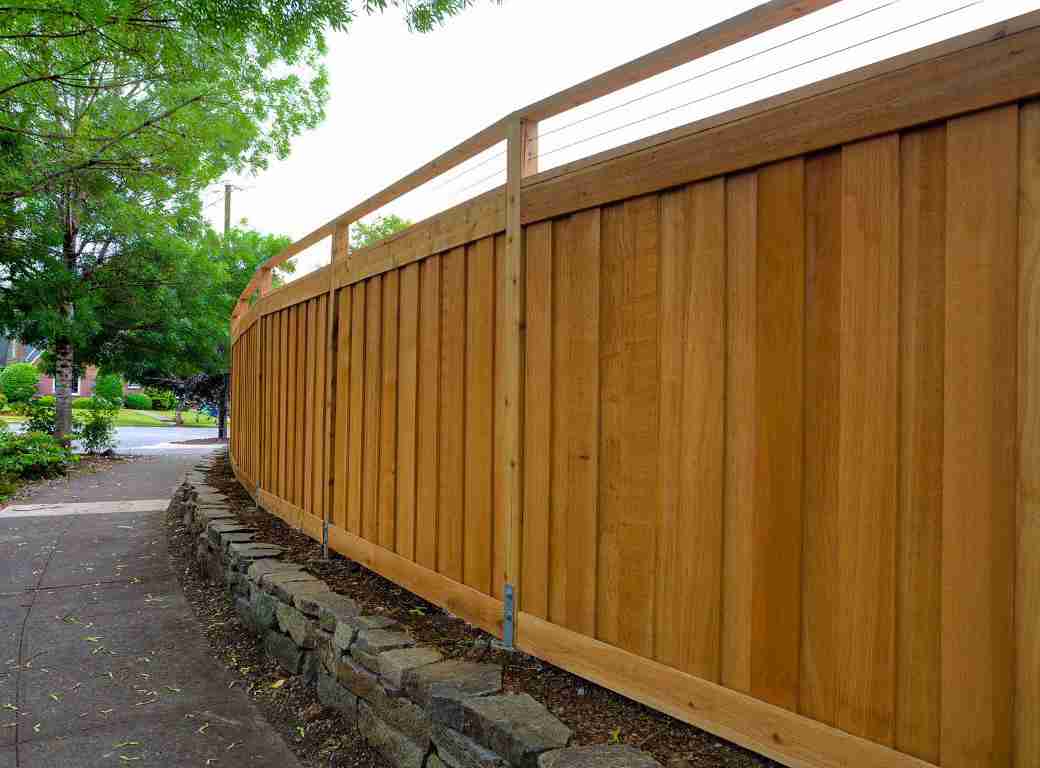 A curved wooden panel fence with unique topper