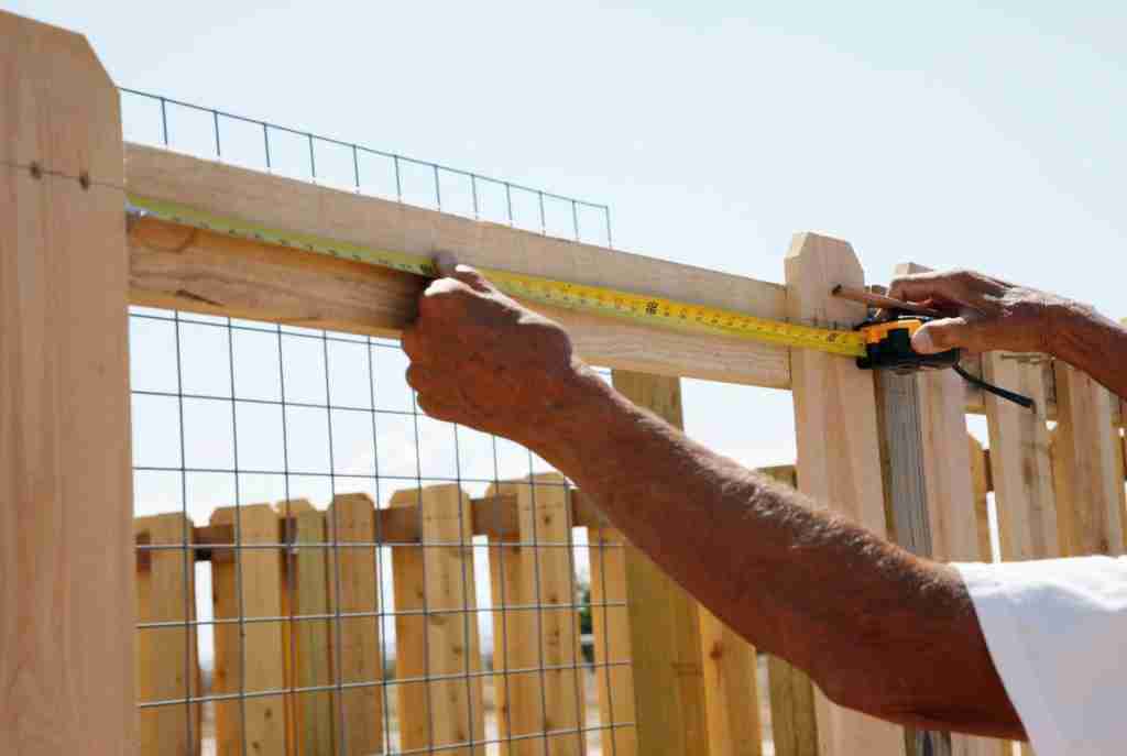 A fence builder installing a wooden privacy fence in Central Texas